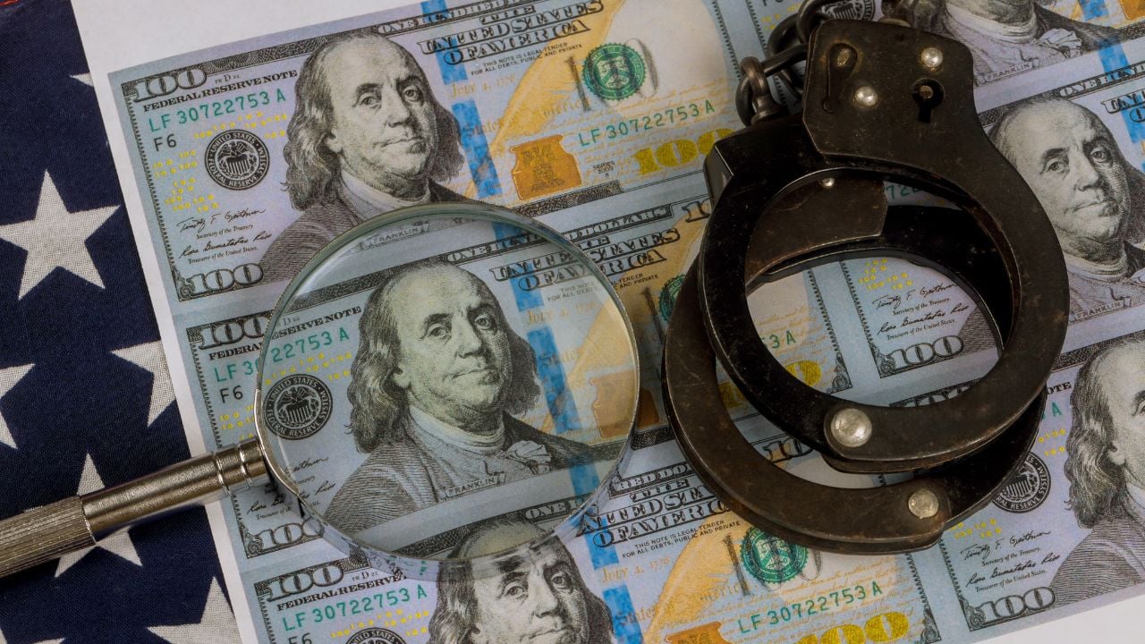 Handcuffs rest top multiple US hundred dollar bills