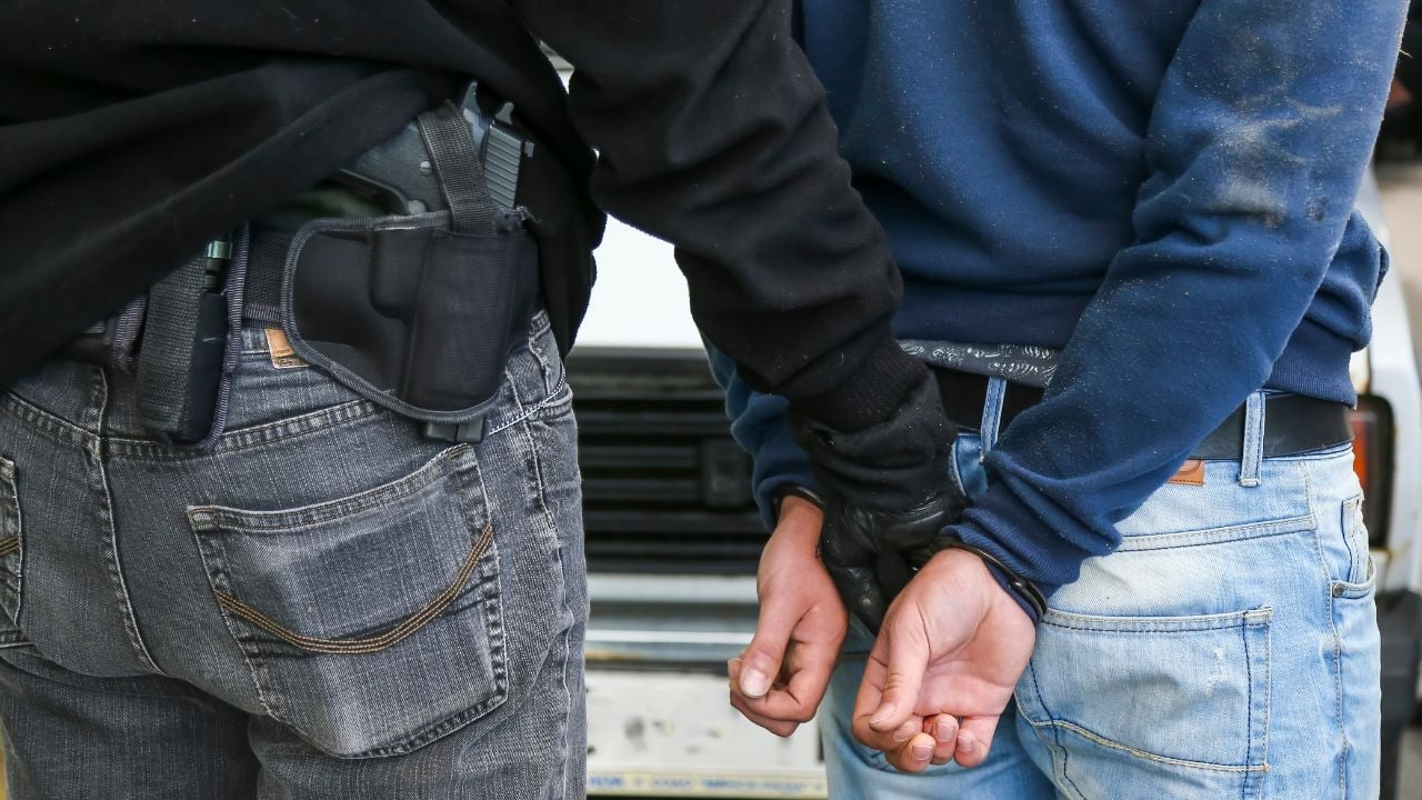 A police officer restrains a suspect in handcuffs