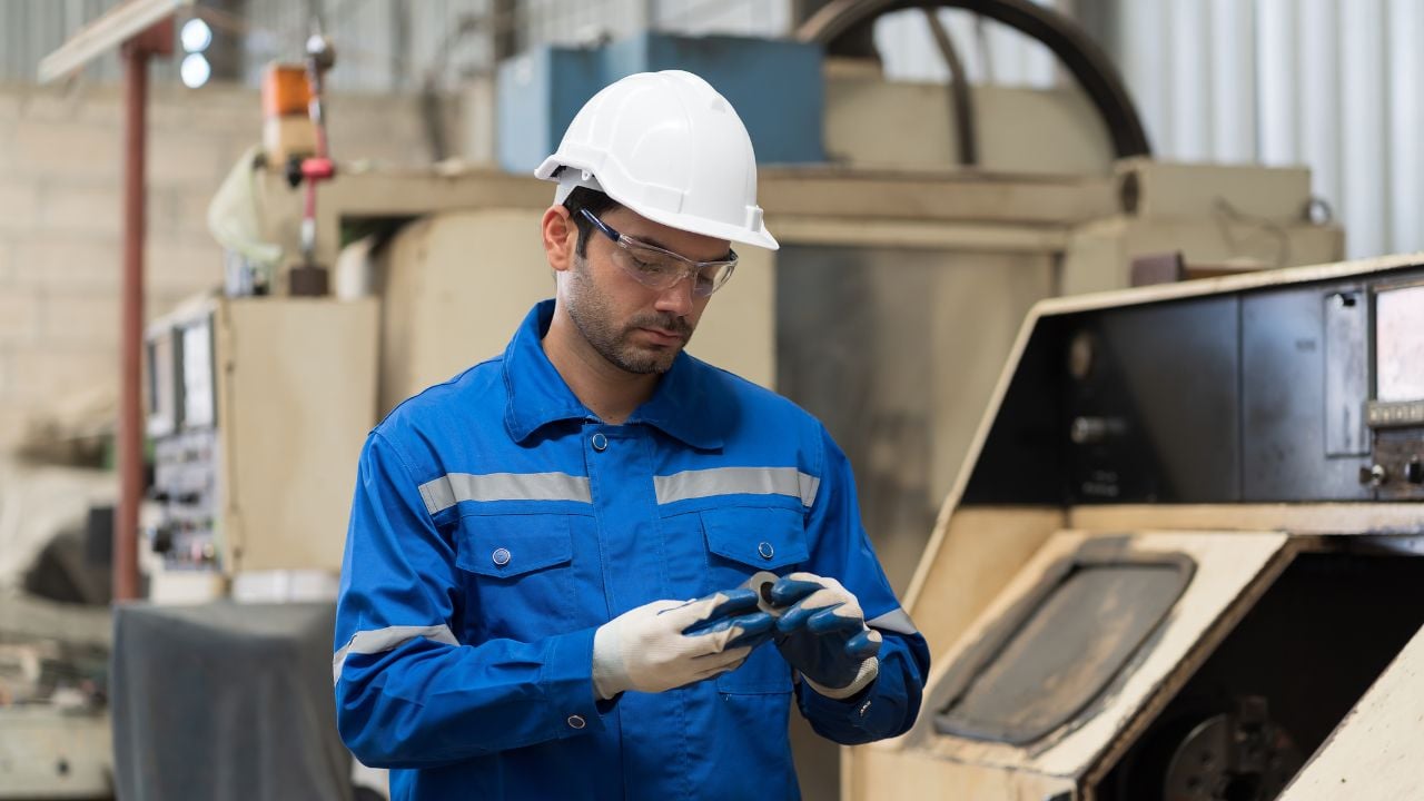 Male engineer worker inspecting quality parts of CNC machine in industrial factory, wearing safety uniform, glasses and hard hat. Technicians installing or replacing parts on CNC machines in factory