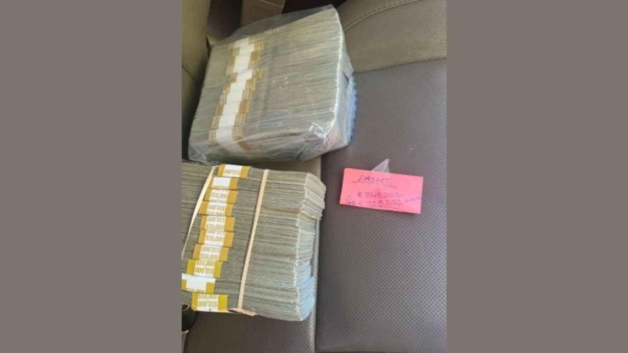 Two large bundled stacks of cash on a vehicle seat beside a pink note, photographed in connection with the federal tax fraud investigation.